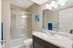 Glass-enclosed shower with tile surround, vanity with an integrated sink, broad mirror, and contemporary light fixture - 