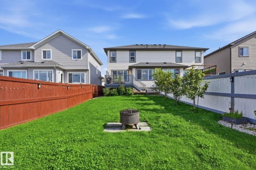 Expansive green lawn with a privacy fence, established trees, and a fire pit - 944 Morris Way, Leduc, AB - Outdoor With Deck Patio Veranda
