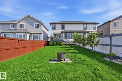 Expansive green lawn with a privacy fence, established trees, and a fire pit - 
