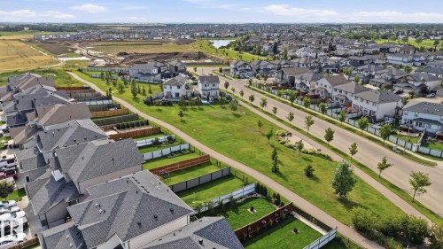 Residential neighborhood featuring paved roadways, individual property fencing, and a developed green space with a walking path - 944 Morris Way, Leduc, AB - Outdoor With View