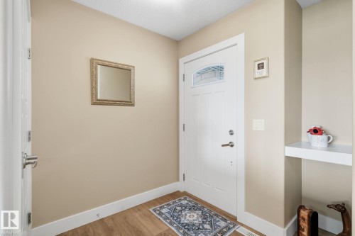 Entryway featuring wood-finish flooring, a white paneled door with decorative glass, and a built-in white shelf - 944 Morris Way, Leduc, AB - Indoor Photo Showing Other Room