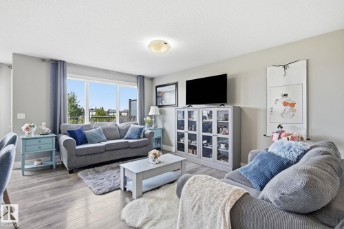 Living space featuring wood-finish flooring, a large window, a ceiling-mounted light fixture, and light gray walls - 944 Morris Way, Leduc, AB - Indoor Photo Showing Living Room