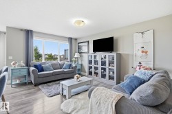 Living space featuring wood-finish flooring, a large window, a ceiling-mounted light fixture, and light gray walls - 