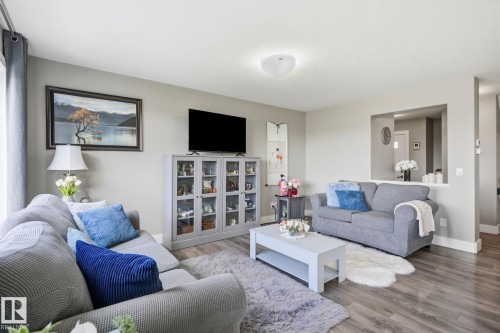 Warm neutral wall paint, wood-finish flooring, recessed wall niche, and built-in display cabinetry - 944 Morris Way, Leduc, AB - Indoor Photo Showing Living Room