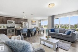Open-concept living space with wood-finish flooring, recessed lighting, and large windows - 