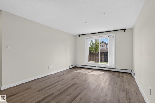 Expansive room with wood-finish flooring and neutral wall tones - #131 5504 Schonsee Dr Nw, Edmonton, AB - Indoor Photo Showing Other Room