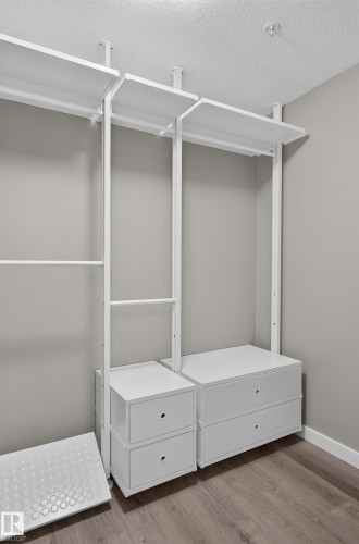 Integrated white closet organization system with hanging rods, shelving, and pull-out drawers - #131 5504 Schonsee Dr Nw, Edmonton, AB - Indoor