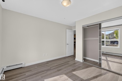 Wood-finish flooring, mirrored closet doors, and light-toned walls - #131 5504 Schonsee Dr Nw, Edmonton, AB - Indoor Photo Showing Other Room