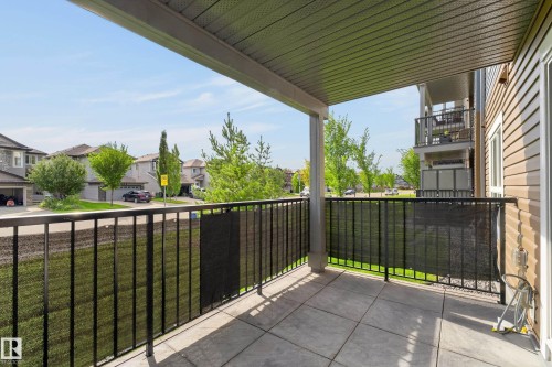 Covered outdoor patio with a concrete surface and a black metal railing - #131 5504 Schonsee Dr Nw, Edmonton, AB - Outdoor With Balcony With Exterior