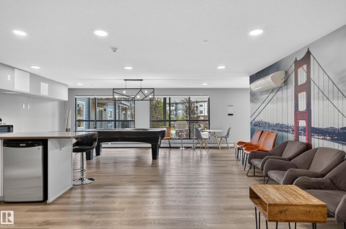 Spacious common area featuring wood-finish flooring, recessed lighting, and large windows - #131 5504 Schonsee Dr Nw, Edmonton, AB - Indoor