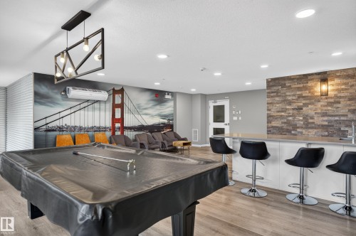 Wood-finish flooring, recessed lighting, and a modern rectangular chandelier illuminate this open space - #131 5504 Schonsee Dr Nw, Edmonton, AB - Indoor