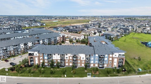 Modern apartment complex with multi-story facades, individual balconies, and surrounding green spaces - #131 5504 Schonsee Dr Nw, Edmonton, AB - Outdoor With View