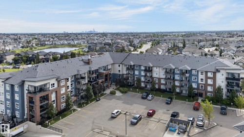 Multi-story residential building with exterior balconies, an on-site parking lot, and surrounding landscaped areas - #131 5504 Schonsee Dr Nw, Edmonton, AB - Outdoor With Balcony With View