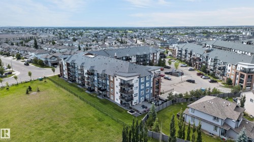 Expansive green space bordering a residential community featuring multi-story apartment buildings with balconies - #131 5504 Schonsee Dr Nw, Edmonton, AB - Outdoor With View