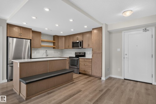 Kitchen featuring a stainless steel refrigerator, stainless steel microwave, and white subway tile backsplash - #131 5504 Schonsee Dr Nw, Edmonton, AB - Indoor Photo Showing Kitchen With Stainless Steel Kitchen