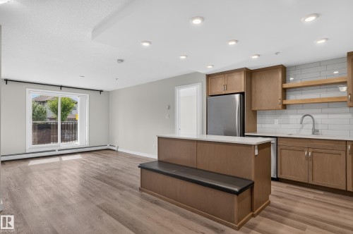 Open-concept living space featuring wood-finish flooring, recessed lighting, and a sliding glass door - #131 5504 Schonsee Dr Nw, Edmonton, AB - Indoor Photo Showing Kitchen