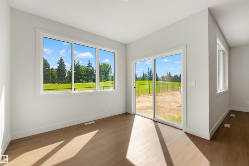 Wood-finish flooring, white trim throughout, large multi-pane window, sliding glass door, white walls - 16 Grayson Green, Stony Plain, AB - Indoor Photo Showing Other Room