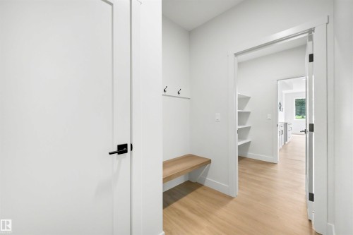 Entryway featuring wood-finish flooring, a built-in wooden bench, wall-mounted coat hooks, and an integrated storage area with shelving - 16 Grayson Green, Stony Plain, AB - Indoor Photo Showing Other Room