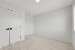 Neutral-toned carpet flooring, white walls, and modern white doors with matte black hardware - 