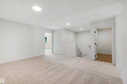 Recessed lighting, large circular ceiling light, carpeted flooring, white walls, interior doorway with wood-finish flooring beyond - 