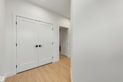 Wood-finish flooring, white walls, and a double door with matte black hardware - 