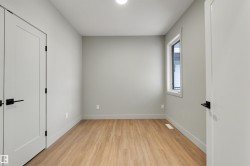 Light wood-finish flooring, a single window, and a white ceiling light fixture - 