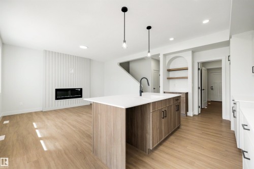 Spacious open-concept living area with wood-finish flooring - 16 Grayson Green, Stony Plain, AB - Indoor Photo Showing Kitchen With Fireplace