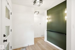 Entryway featuring a striking green accent wall, sconce lighting, and a dark floating shelf - 