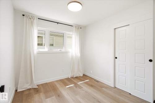 Bright interior space featuring a window with white trim, wood-finish flooring, and a flush mount ceiling light - 4708 104A Avenue Nw, Edmonton, AB - Indoor Photo Showing Other Room