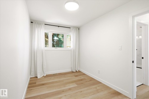 Bright room featuring wood-finish flooring, white walls, and a window with white trim - 4708 104A Avenue Nw, Edmonton, AB - Indoor Photo Showing Other Room