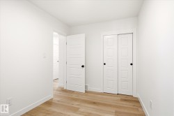 Bright interior room featuring wood-finish flooring, white walls, and a white sliding closet door - 