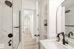 Contemporary bathroom featuring a black-framed mirror and a white vanity with an integrated sink - 