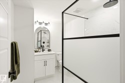 Modern bathroom featuring a walk-in shower with a black-framed opaque panel and a rainfall showerhead - 