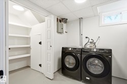 Dedicated laundry area featuring a washer and dryer, adjacent built-in shelving, white walls, and a drop ceiling - 