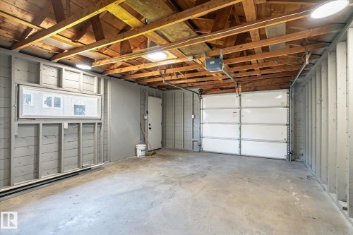 Single-car garage featuring a concrete floor, exposed wood beam ceiling, and a white paneled garage door - 4708 104A Avenue Nw, Edmonton, AB - Indoor Photo Showing Garage