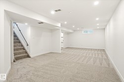 Spacious room featuring light-toned carpet flooring, white walls, and recessed lighting - 