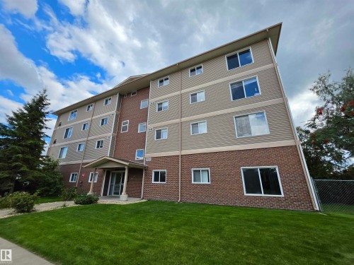 Multi-story building featuring a brick base and horizontal siding, multiple windows, and a covered main entrance - #207 8117 114 Av Nw, Edmonton, AB - Outdoor