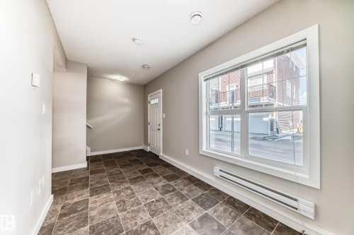 Tile flooring, white trim work, baseboard heating, recessed lighting, and a front entry door with a privacy window - #75 2803 James Mowatt Tr Sw, Edmonton, AB 
