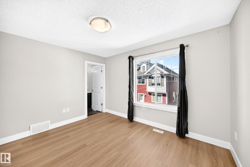 Wood-finish flooring with white trim, light gray walls, and a large window - #75 2803 James Mowatt Tr Sw, Edmonton, AB 