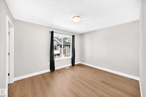 Light gray wall paint, wood-finish flooring, white window trim, and a ceiling-mounted light fixture - #75 2803 James Mowatt Tr Sw, Edmonton, AB 