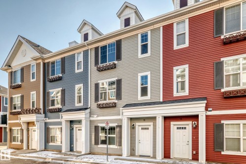 Multi-level facade featuring horizontal siding, white window trim, functional shutters, and decorative window boxes - #75 2803 James Mowatt Tr Sw, Edmonton, AB 
