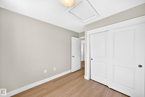 Neutral tone wall paint, wood-finish flooring, bright white trim, paneled interior doors, and a ceiling-mounted light fixture - #75 2803 James Mowatt Tr Sw, Edmonton, AB 