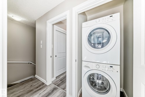 Recessed laundry area with stacked white appliances - #75 2803 James Mowatt Tr Sw, Edmonton, AB 