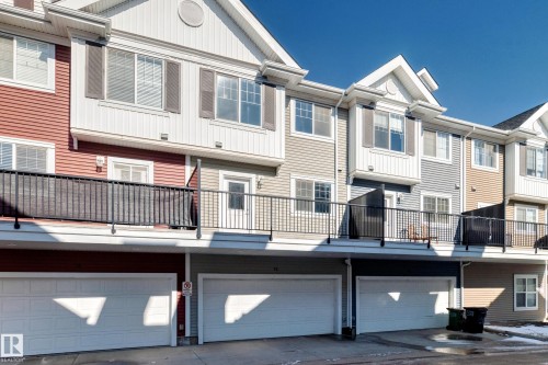 Multi-level townhome featuring a private balcony with black metal railings, individual garage access, and gabled rooflines - #75 2803 James Mowatt Tr Sw, Edmonton, AB 