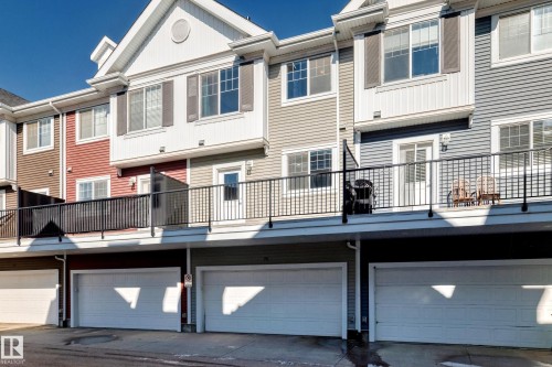 Townhome exterior featuring multi-level siding, white trim, private balconies with black railings, and integrated garage bays - #75 2803 James Mowatt Tr Sw, Edmonton, AB 
