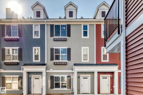 Vibrant multi-colored siding, multiple dormer windows, decorative window boxes, black louvered shutters, and white paneled entry doors - #75 2803 James Mowatt Tr Sw, Edmonton, AB 