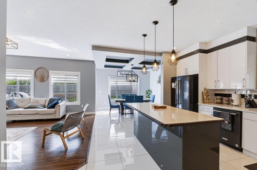Gourmet kitchen with an expansive island, light-toned countertops, and glossy white cabinetry - 527 Merlin Landing Nw, Edmonton, AB - Indoor Photo Showing Kitchen With Upgraded Kitchen