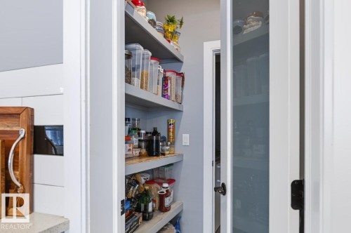 Walk-in pantry with multiple built-in shelves and a white interior door - 527 Merlin Landing Nw, Edmonton, AB - Indoor