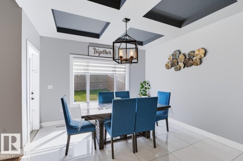 Recessed ceiling design with dark accents, contemporary light fixture, large window with horizontal blinds, white tile flooring, and light gray wall paint - 527 Merlin Landing Nw, Edmonton, AB - Indoor Photo Showing Dining Room