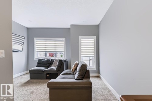 Recessed ceiling lighting, light gray wall paint, white window trim, and textured carpeting - 527 Merlin Landing Nw, Edmonton, AB - Indoor Photo Showing Living Room